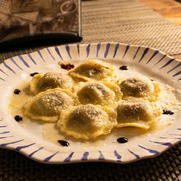 Seven ravioli with cheese and sauce on a white plate with blue stripes on a wooden table.